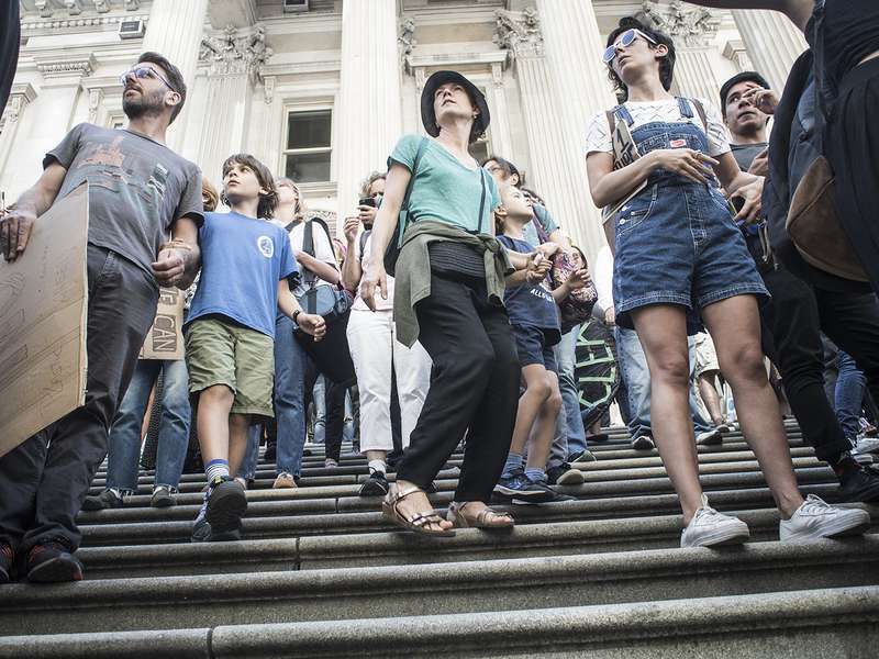 A group of people standing on steps, holding signs and participating in a movement.