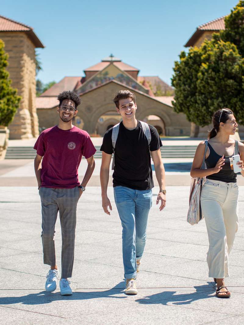 Three students happily walking through the quad.