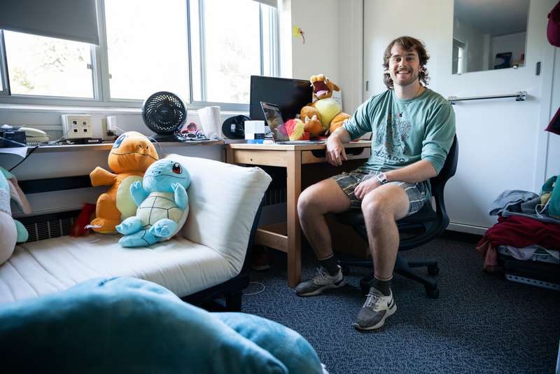 Student at his desk in his dorm room with dinosaur stuffed animals