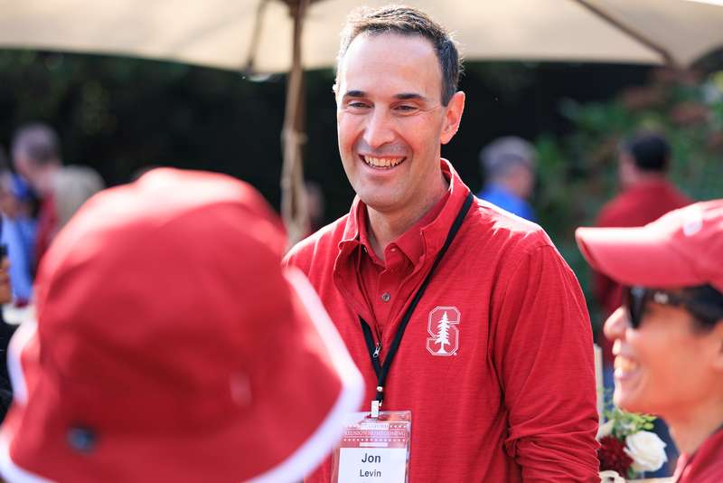 Jon Levin talking with attendees of the Class of 94 reunion outdoors on a sunny day.