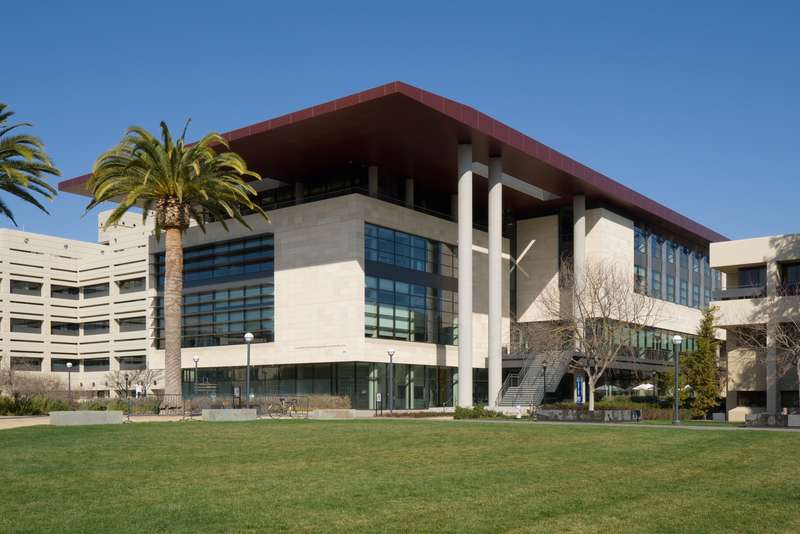 Stanford Medicine's Li Ka Shing Learning and Knowledge Center on a clear sunny day with green grass and palm trees in the foreground.
