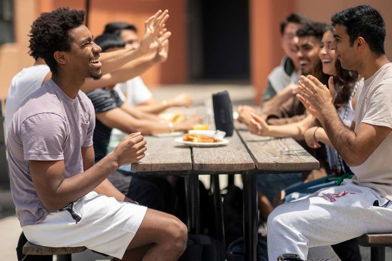 Students laughing, sitting at a picnic table