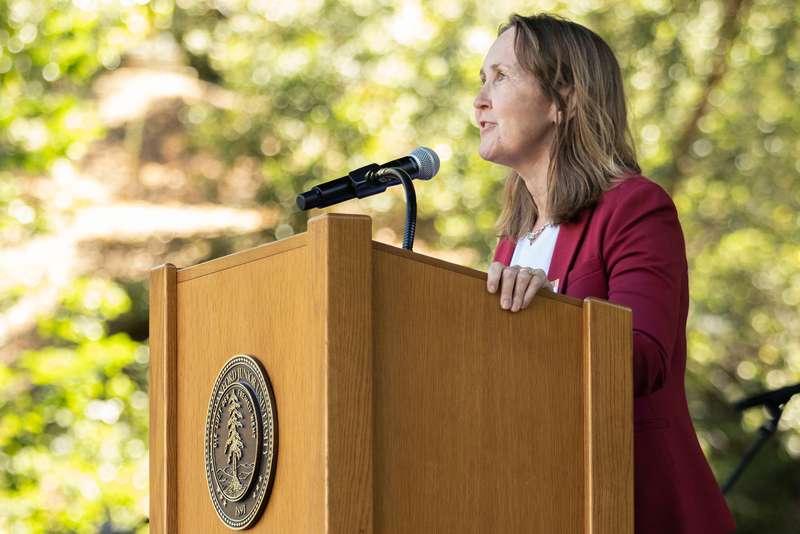 Jenny Martinez speaks at a podium featuring the Stanford University seal during an outdoor event.