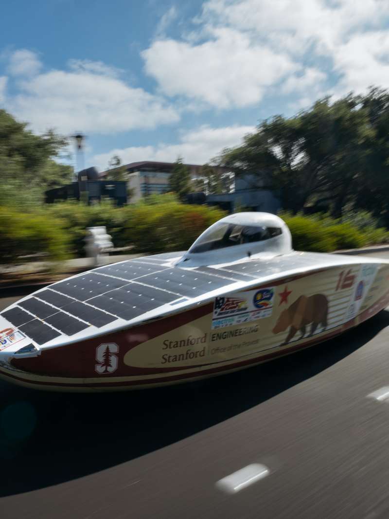 A solar car races down a Stanford campus road