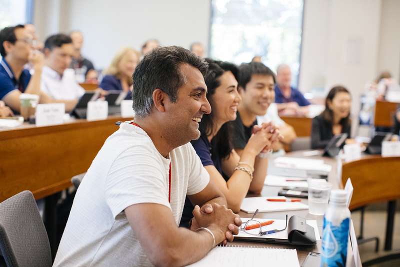 A group of participants attentively listening and engaged during a class or meeting in a conference room setting.
