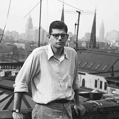 Young Allen Ginsberg stands on a rooftop with a skyline view of buildings, including the Empire State Building
