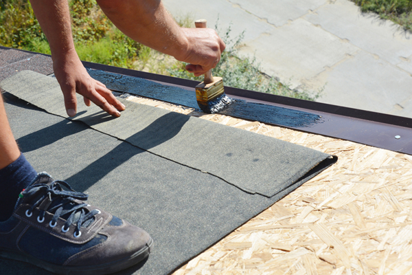 Roofer adhering a modified bitumen membrane