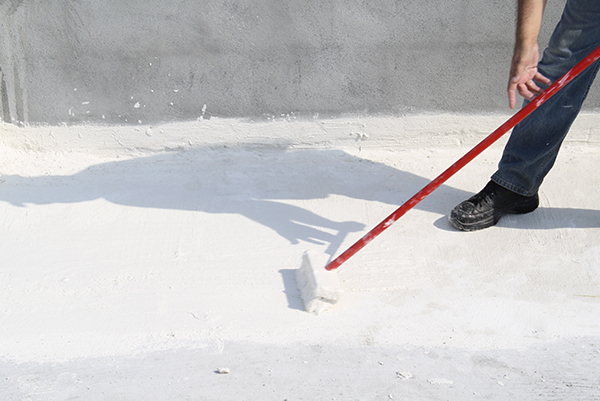 A roofer applying a white roof coating.