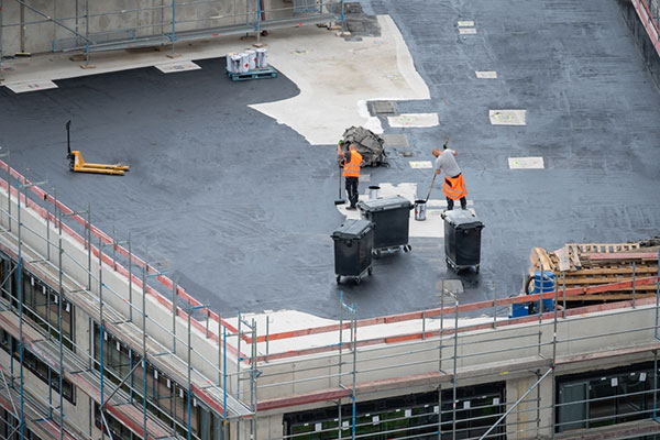 A roofing contractor applying a coating to a flat roof.