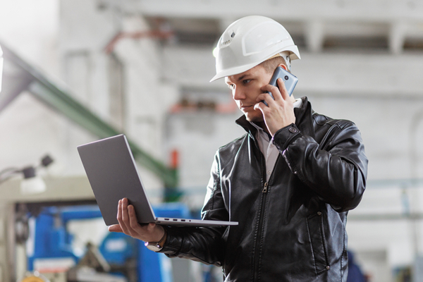 A roofing contractor reviews his upcoming projects on a laptop while corresponding with clients