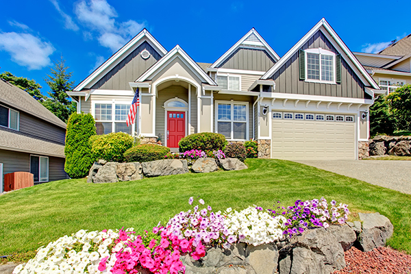 A home with a multi-slope roof and blooming spring flowers.