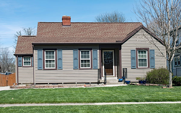A tan one-story house with aluminum siding and blue shutters.