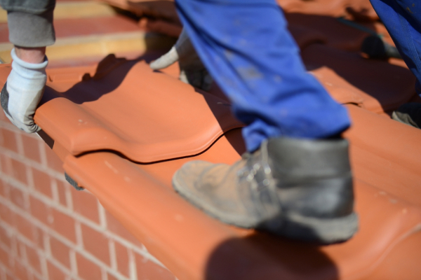 Close-up of roofing shoes and roofer's hands repairing a roof.