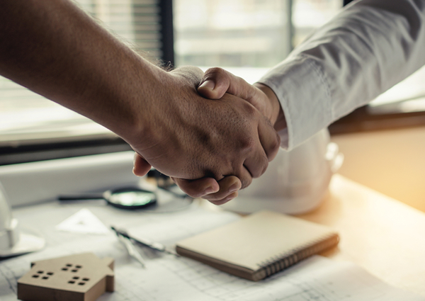 Two people shaking hands in a contractor's office.