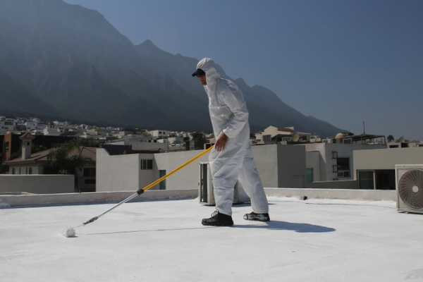 A contractor applies an elastomeric coating to a rooftop.