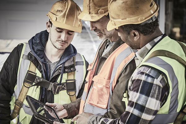Two smiling contractors working together with a laptop and notebook