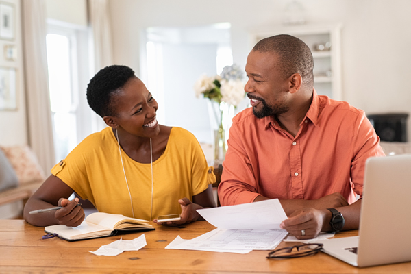 Smiling couple working on a budget with papers and laptop