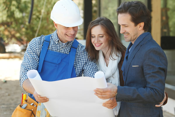Contractor and homeowners looking at blueprint outdoors