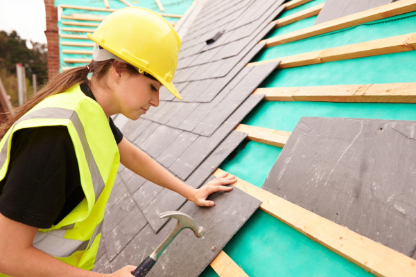 A female roofing contractor works on a roof.