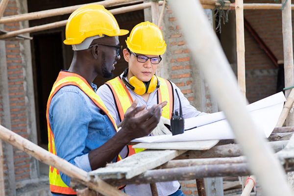 Two commercial contractors talking over plans on a jobsite