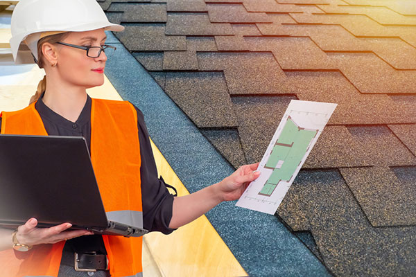 Roofing employee in vest and hard hat reviews job plans