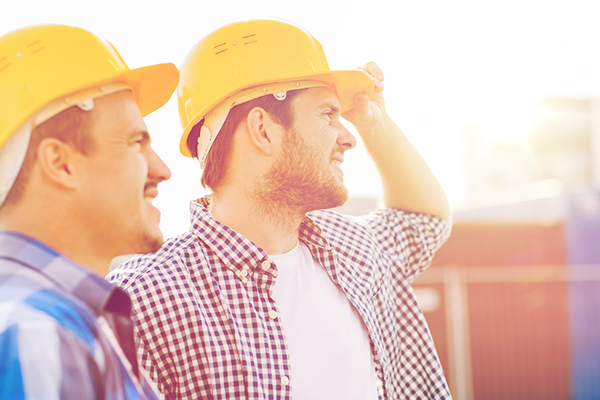 Two roofers in hard hats look to the right.