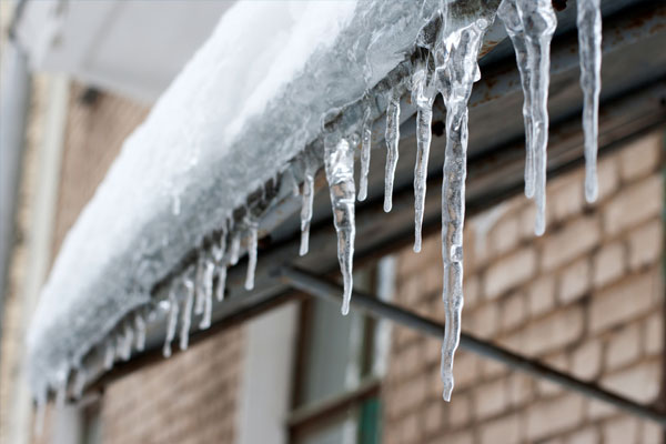 A snowy roof with icicles dangling along the edge