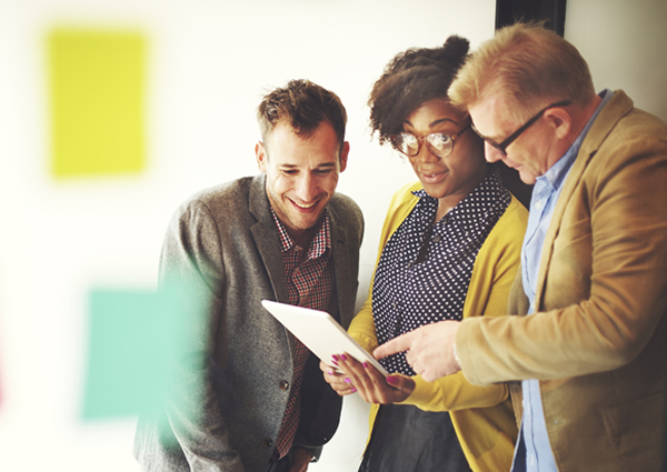 Group of three employees reviewing ways to give back to the community on a tablet