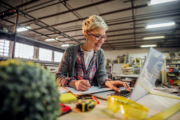 Roofer using laptop in a workshop.