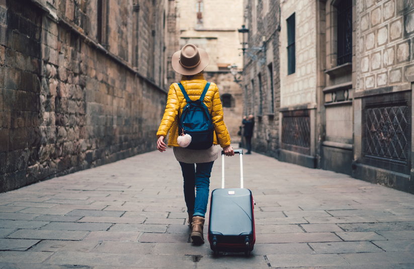 woman walking with a suitcase in a narrow stone-paved street
