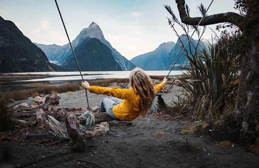 woman on a swing in front of majestic water and mountains in New Zealand