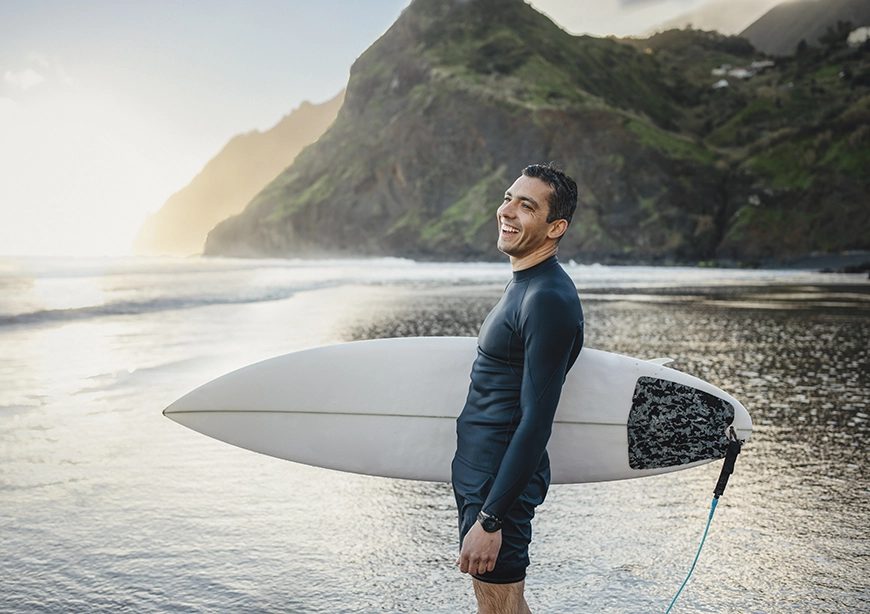 Man carrying surfboard on Hawaiian beach