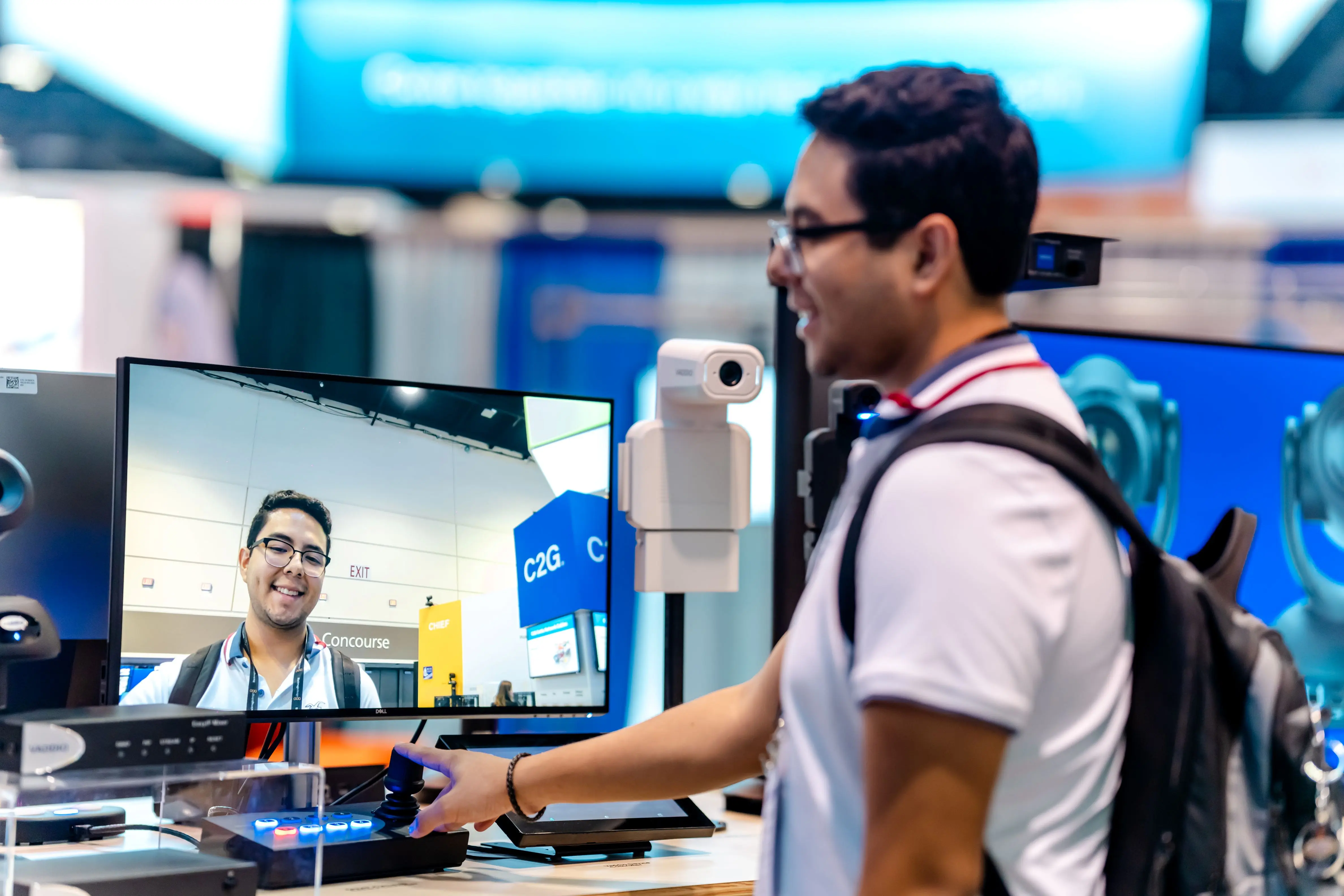 A person interacting with a display screen showing a live video of themselves, smiling, at a tech exhibition booth.