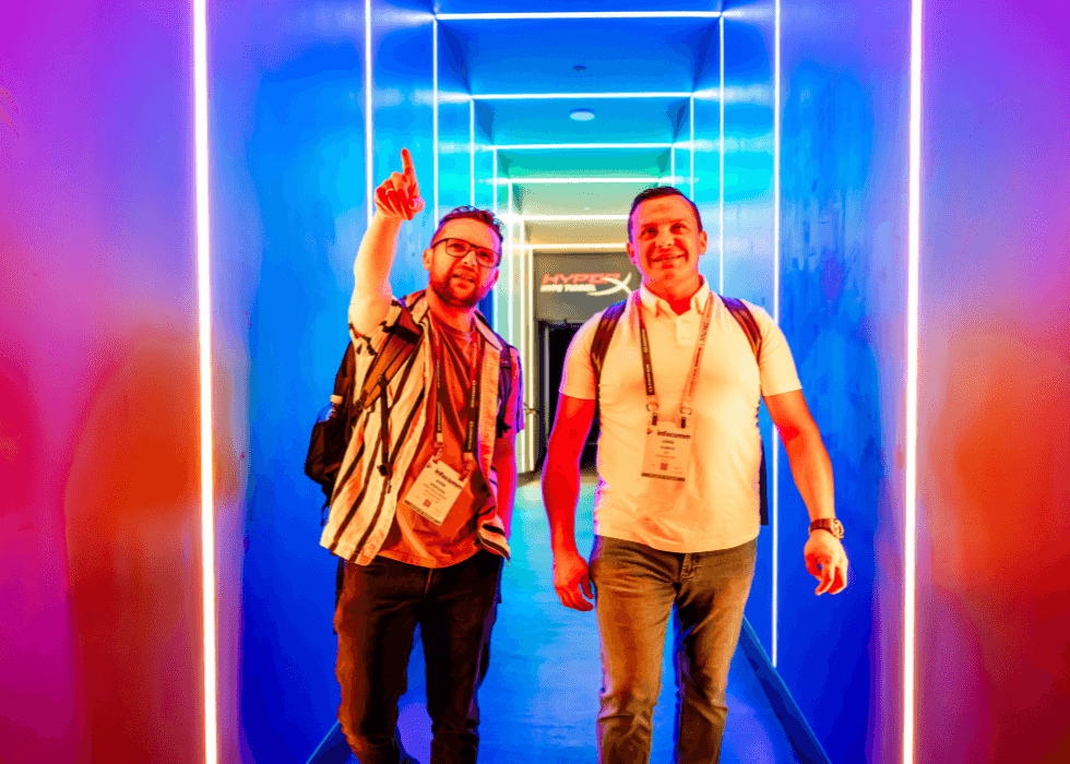 two men walkign through a colored lit hallway