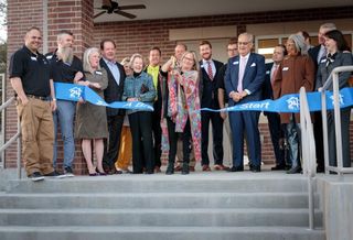 Former Dallas 24 Hour Club Board Chair Shelley Travell cuts the grand opening ribbon
