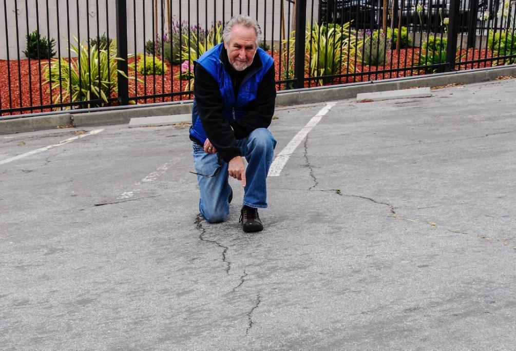 U.S. Geological Survey earthquake geologist David Schwartz assesses cracks in the asphalt parking lot near the Hayward Fault. The cracks show creep, which is characteristic of movement of the Hayward Fault.
