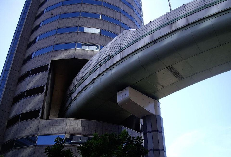 This building is easily recognized by the Hanshin Expressway onramp located within (yes, within) the tower. In the early 1980s, redevelopment of the was approved by the city but building permits stalled because the highway was in planning. Property rights holders negotiated with the Hanshin Expressway for five years before agreeing to jointly develop Gate Tower Building and the highway.