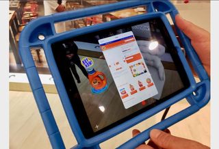 Thyng CEO Ed LaHood (not pictured) demonstrates environmental based augmented reality by holding up a smart tablet over the floor where a digital overlay of a Tide detergent product appears. When customers click on the digital product, it takes them to a website where they can order it. 
