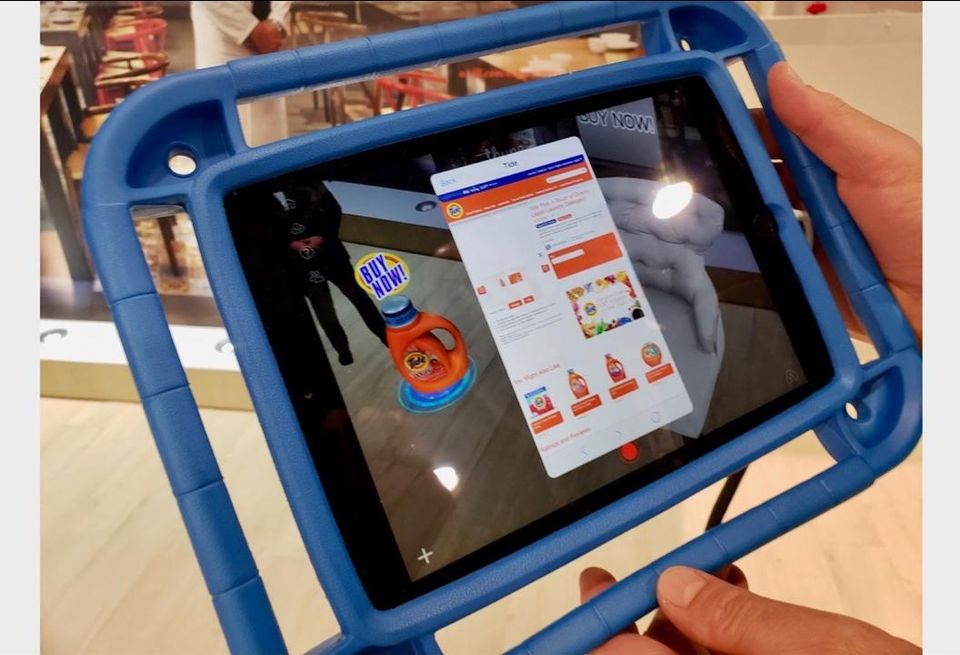 Thyng CEO Ed LaHood (not pictured) demonstrates environmental based augmented reality by holding up a smart tablet over the floor where a digital overlay of a Tide detergent product appears. When customers click on the digital product, it takes them to a website where they can order it. 