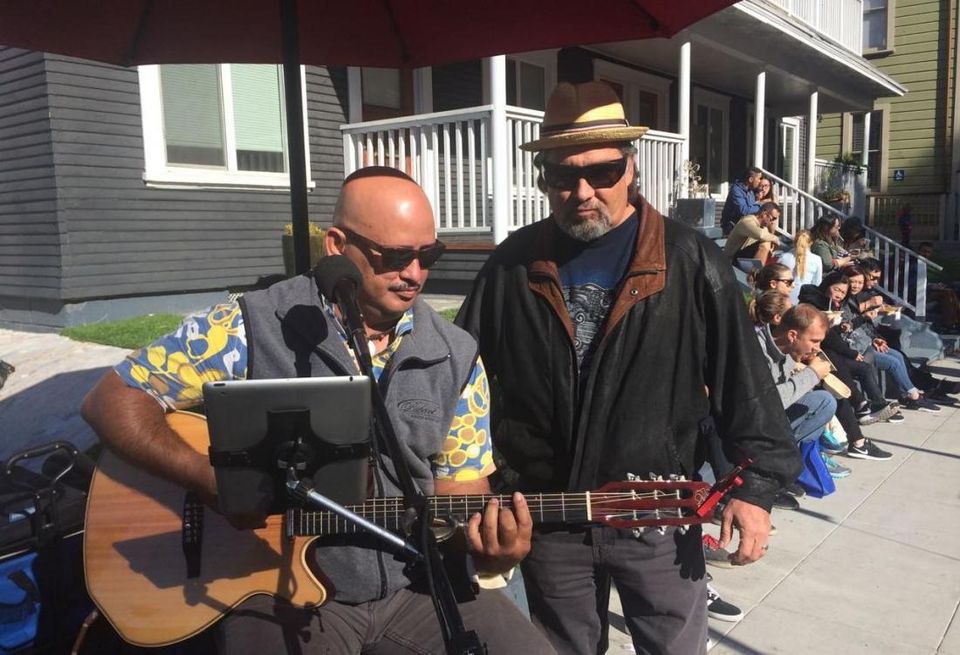 Randy Belcher-Torres, right, legislative chair for the San Diego County Hispanic Chamber of Commerce, joins in song with street musician at the Little Italy Mercato