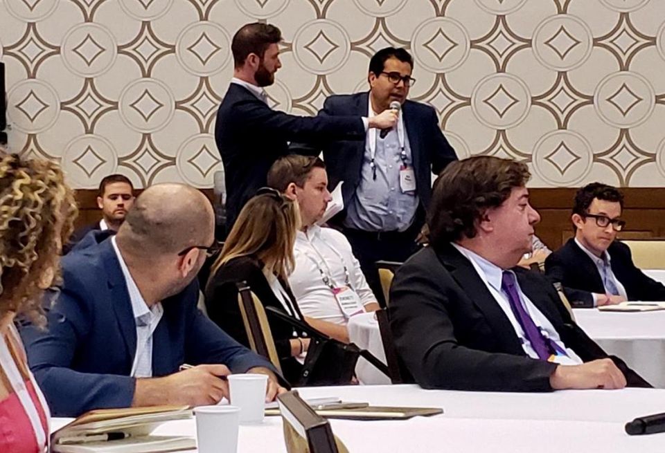 Bisnow's Michael Guimond holds up the mic to an attendee asking a question about Costa-Hawkins.