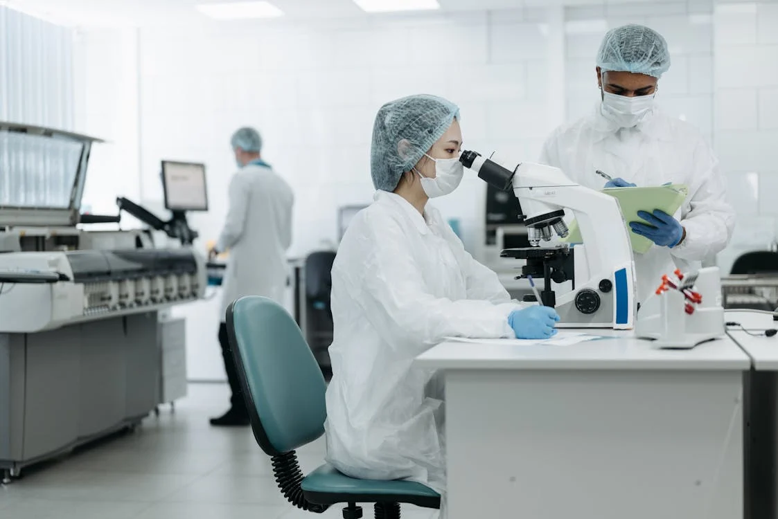 Two medical people at a laboratory looking through a microscope