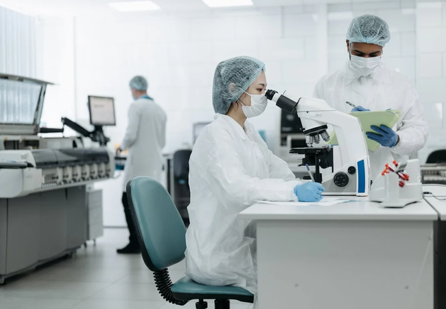 Two medical people at a laboratory looking through a microscope