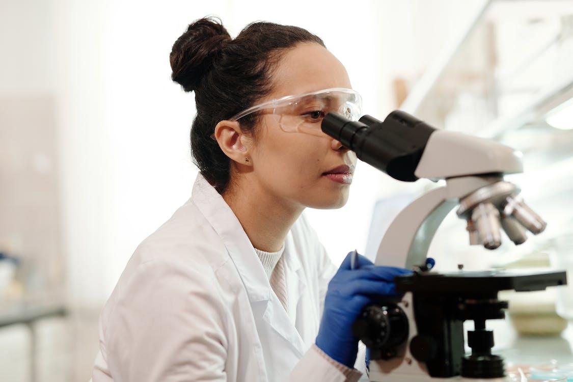Scientist in a lab coat looking through microscope