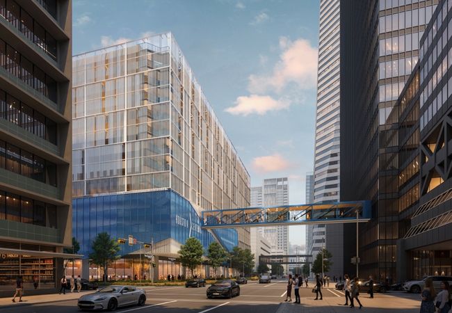 A modern urban street scene with tall glass buildings, a pedestrian skybridge, parked cars, and people walking along the sidewalks under a clear sky.