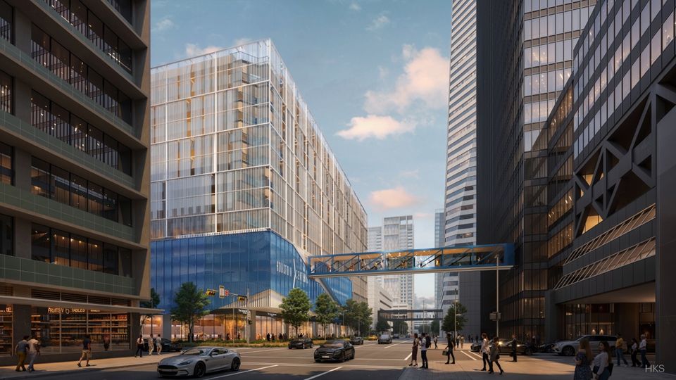 A modern urban street scene with tall glass buildings, a pedestrian skybridge, parked cars, and people walking along the sidewalks under a clear sky.