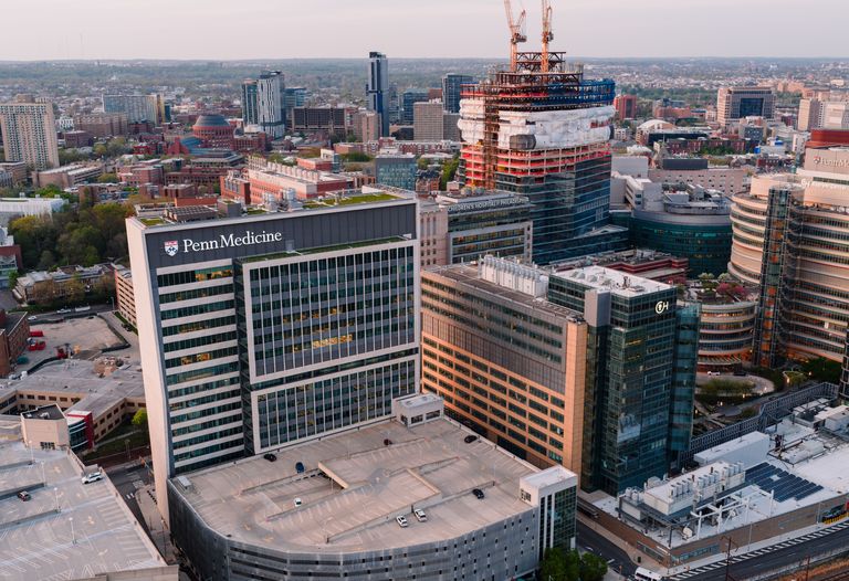 Aerial view of Penn Medicine building in Philadelphia, surrounded by other high-rise structures and ongoing construction, with a cityscape backdrop.