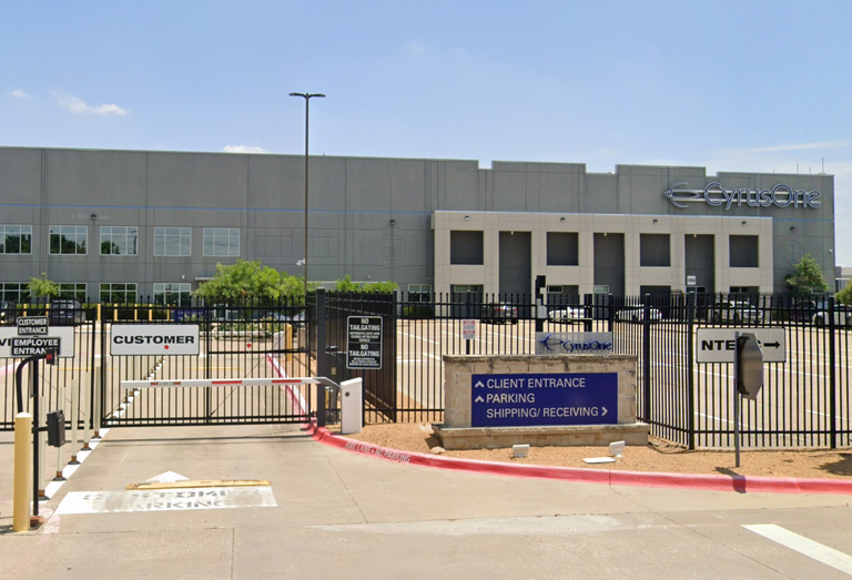 Industrial building with "CyrusOne" signage, fenced entrance, labeled for customer and client entry. Signs indicate no tailgating and directions for parking.