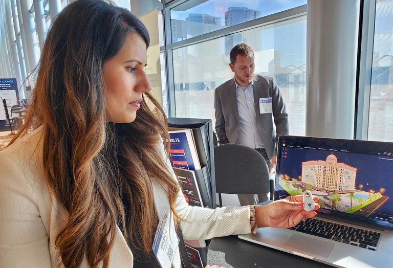 A Wrkspot employee holds up a panic button in front of a demonstration of the company's new software at the ALIS Conference at the JW Marriott in downtown Los Angeles