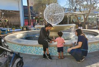 A young boy plays in front of an outdoor water fountain at the opening of CenterCal Properties' 2nd & PCH shopping center in Long Beach